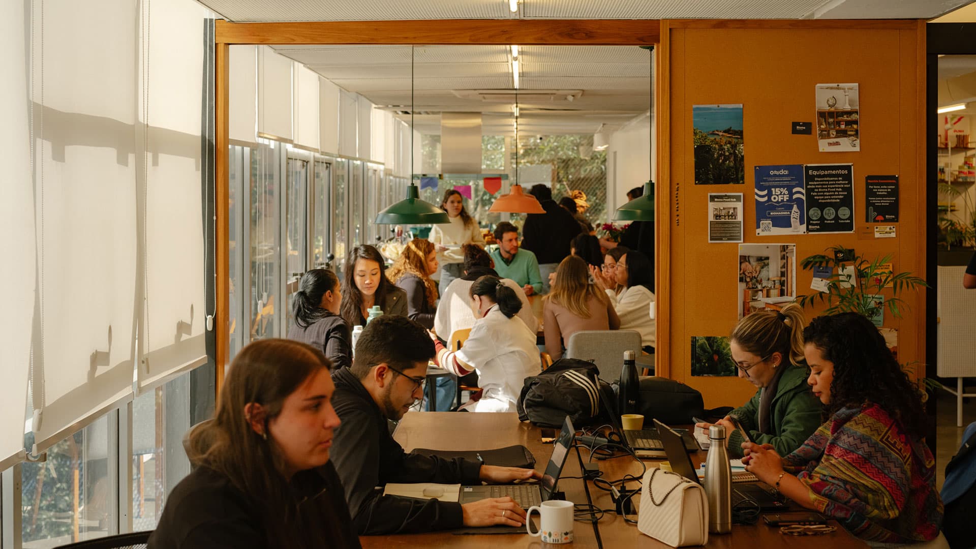 Refeitório do Bioma cheio, com pessoas almoçando em mesas comunitárias
